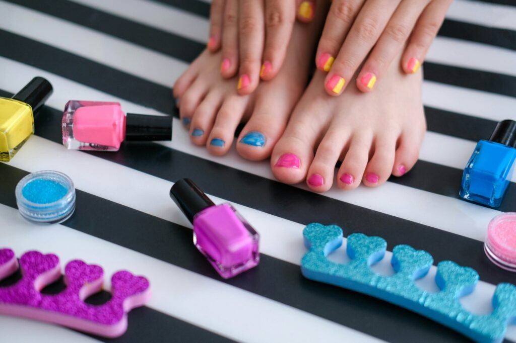 Children's feet with bright pedicure and manicure of colors and bottles of bright nail polish.